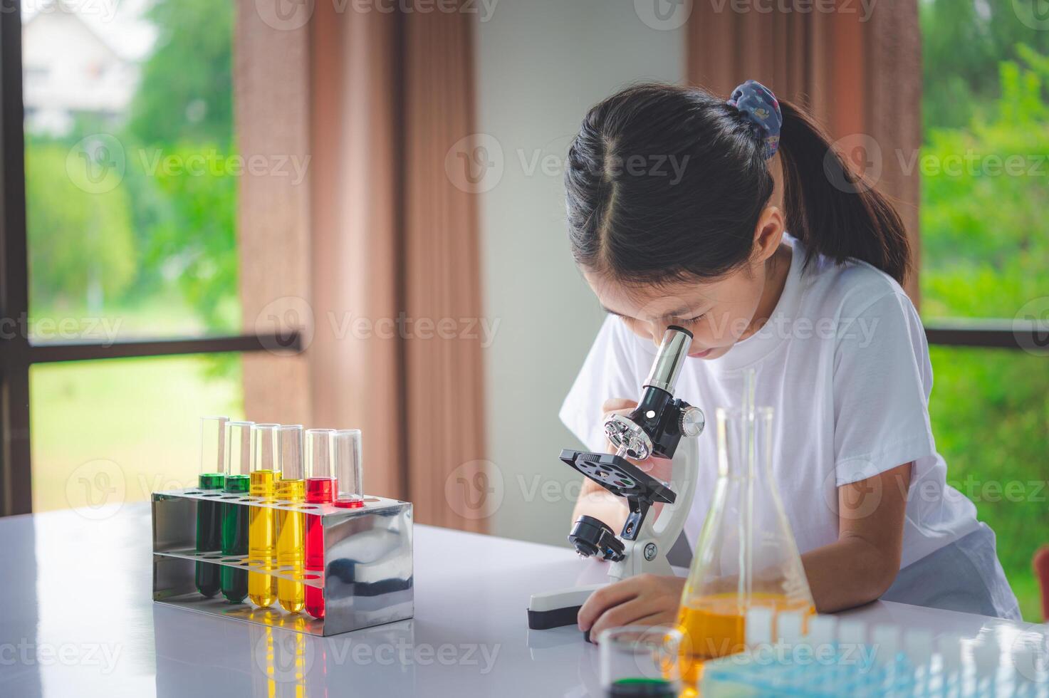 little scientist looking through a microscope and test tubes filled with chemicals for learning about science and experiments. photo