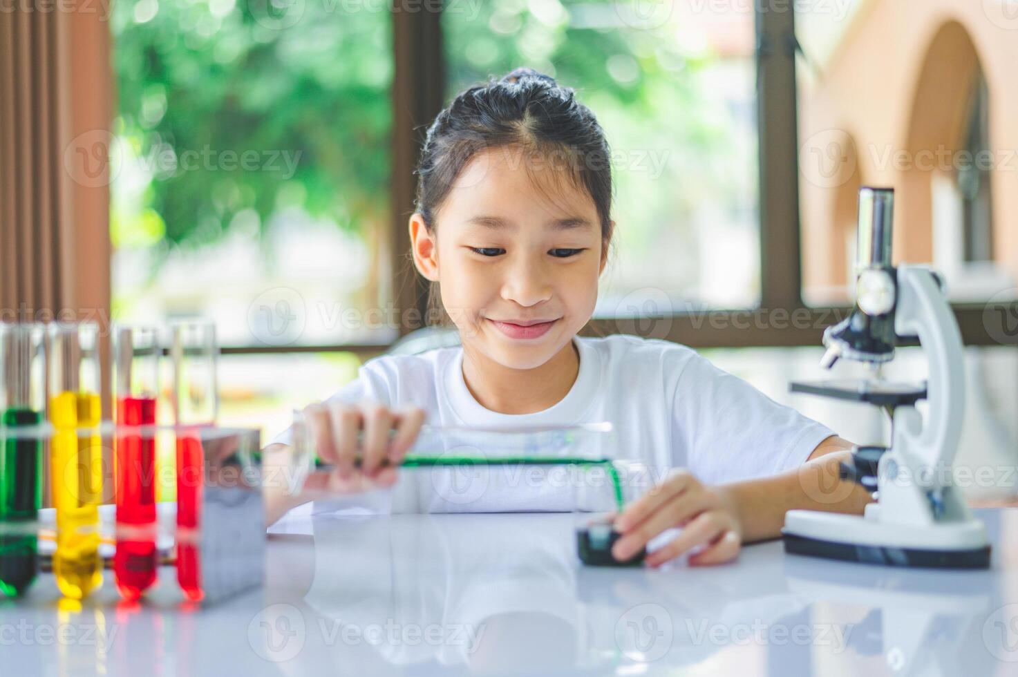 little scientist looking through a microscope and test tubes filled with chemicals for learning about science and experiments. photo