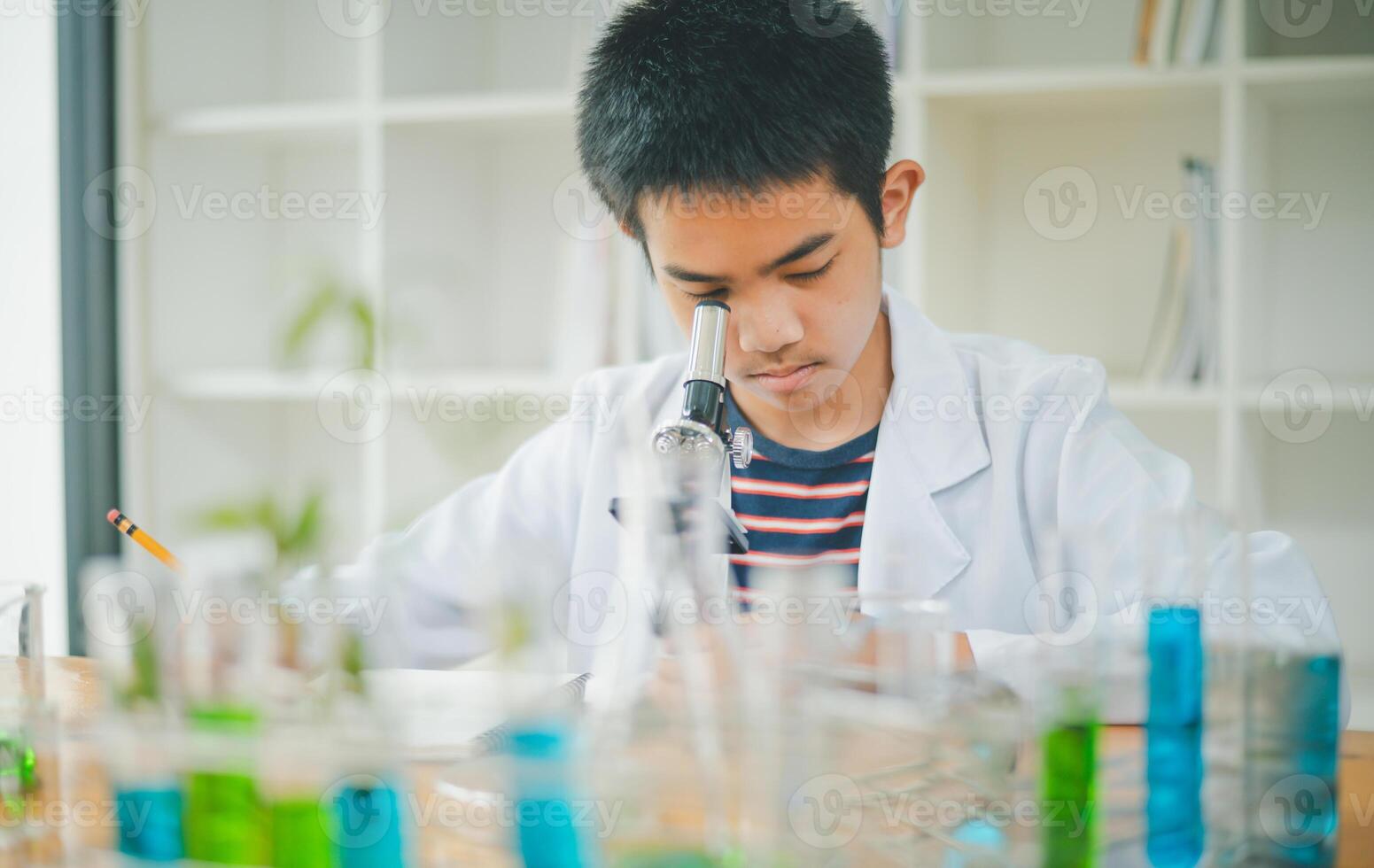 Asian male science students looking through a microscope and tests of plants in the classroom. Learning about scientific experiments on plant species. photo