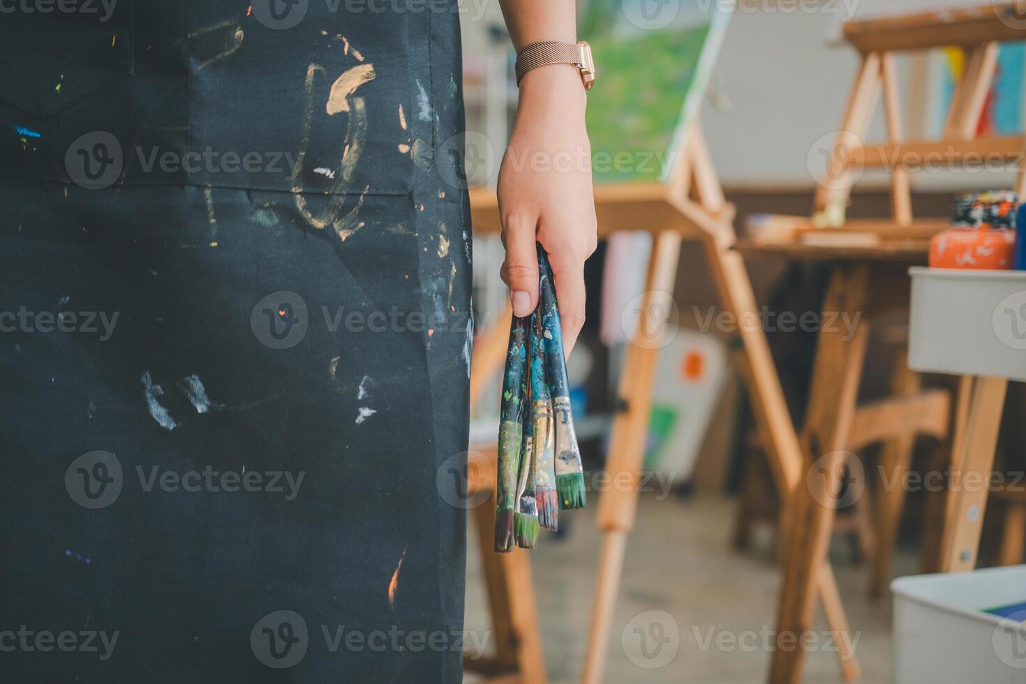Close-up art student's hand holding paintbrush to watercolor painting on canvas doing some art projects photo