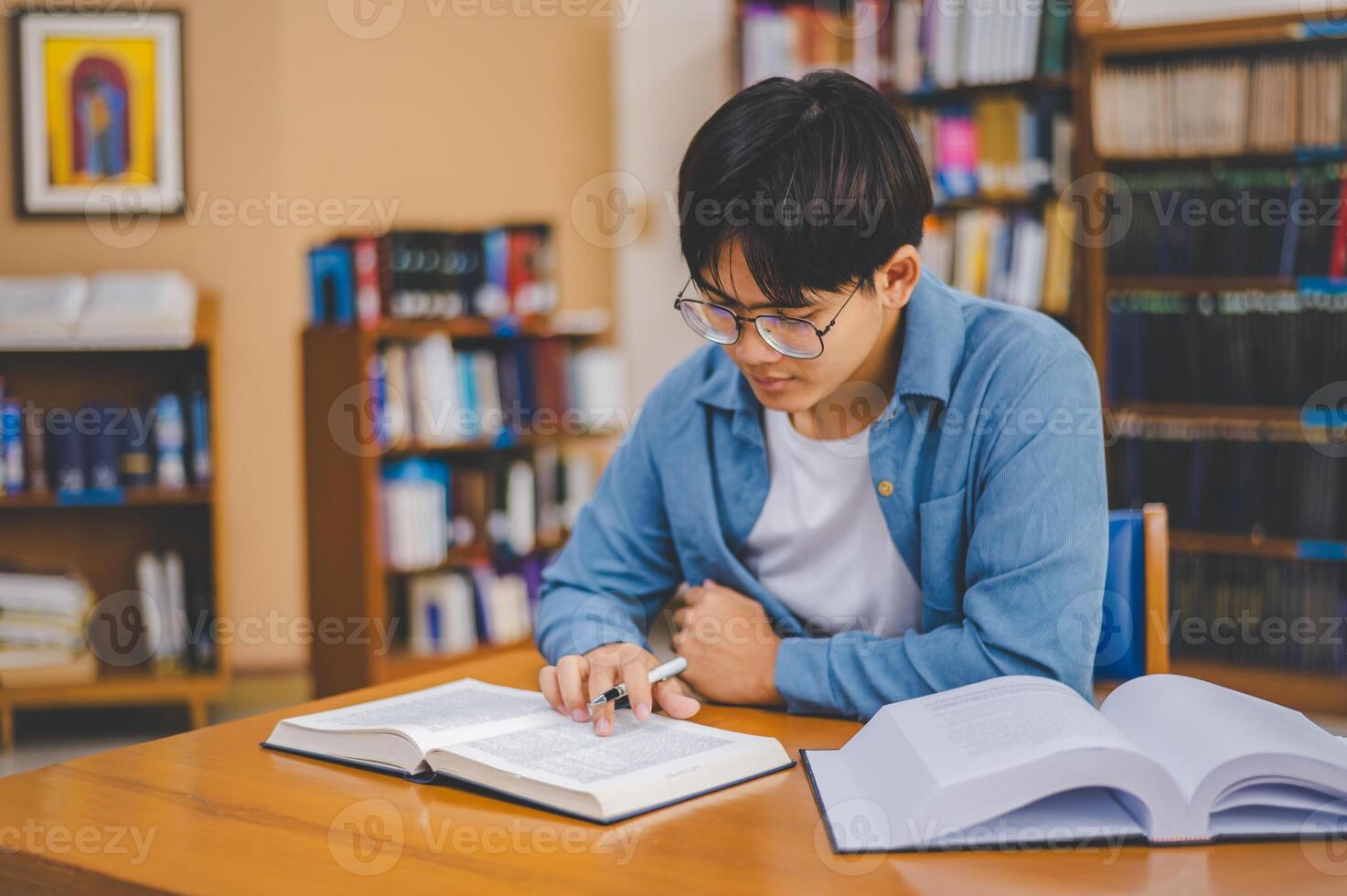 Male college students are working on laptops and searching for books to study, make reports, find useful information in college room. Concept of reading, learning and intelligence. photo