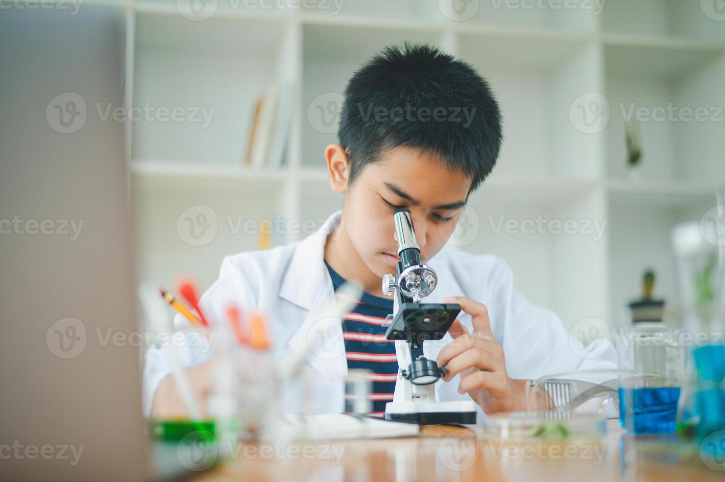 Asian male science students looking through a microscope and tests of plants in the classroom. Learning about scientific experiments on plant species. photo