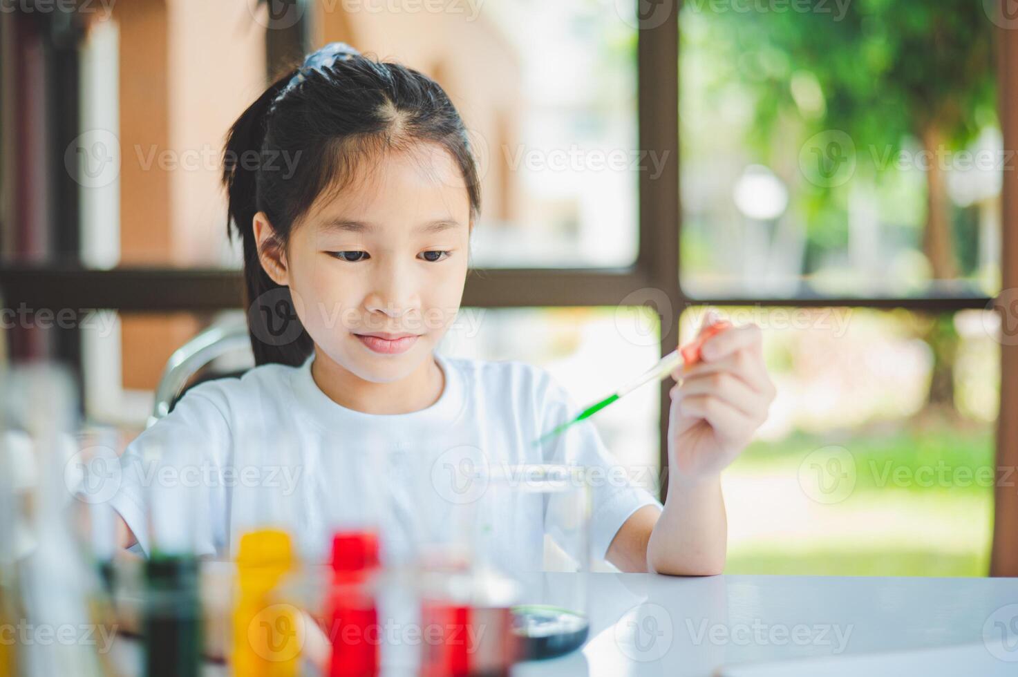 little scientist looking through a microscope and test tubes filled with chemicals for learning about science and experiments. photo
