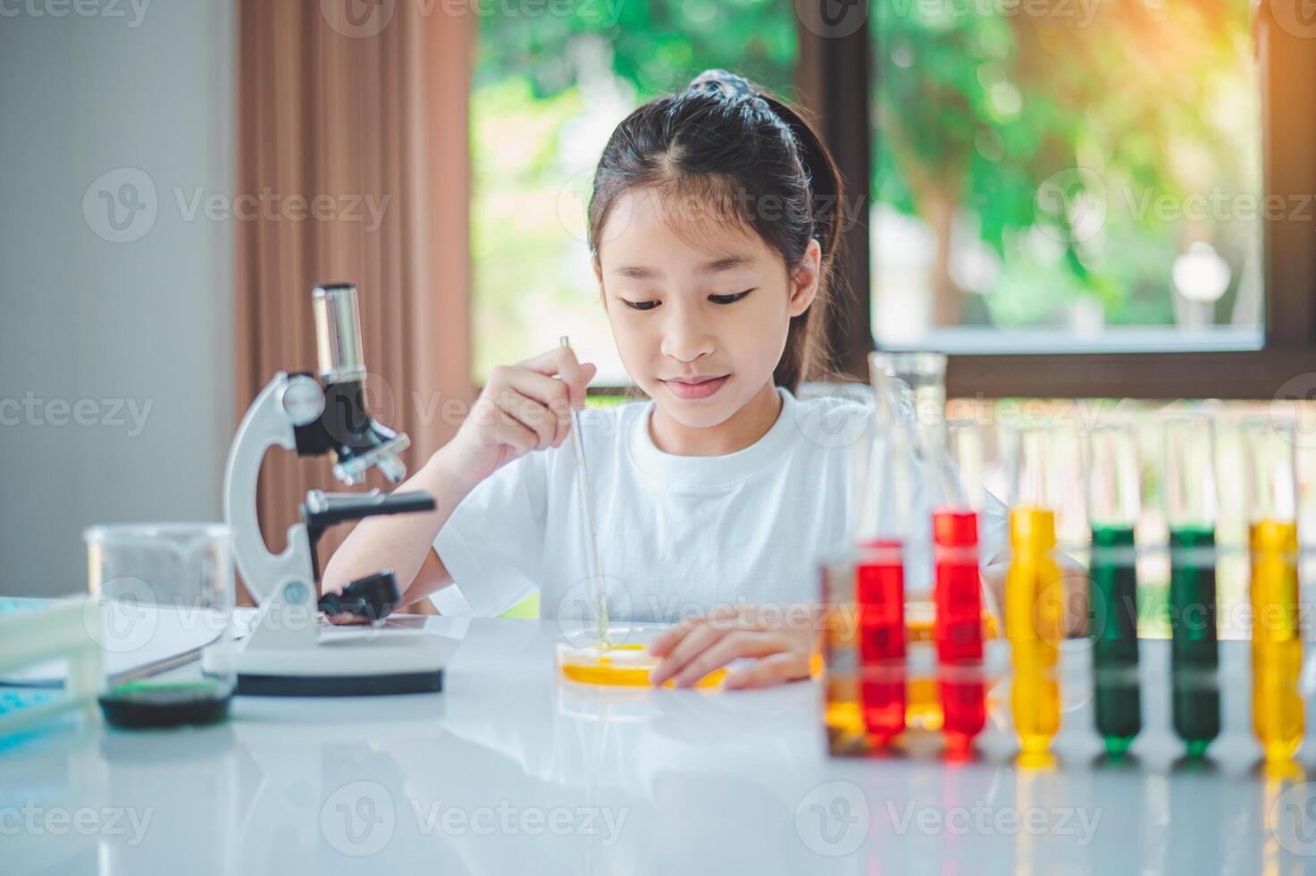 little scientist looking through a microscope and test tubes filled with chemicals for learning about science and experiments. photo