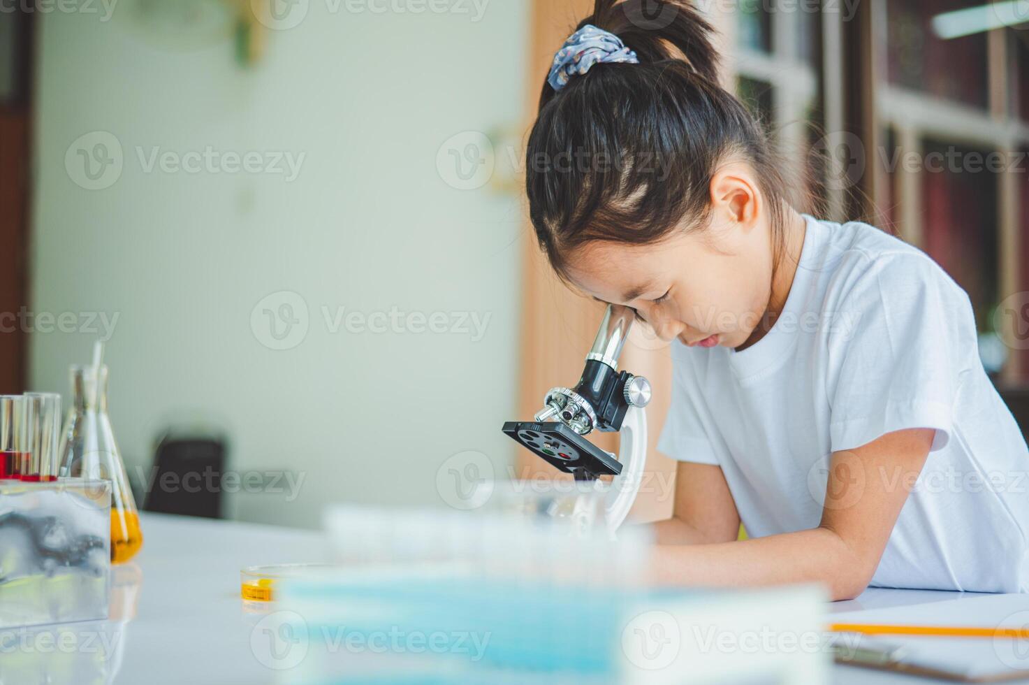 little scientist looking through a microscope and test tubes filled with chemicals for learning about science and experiments. photo