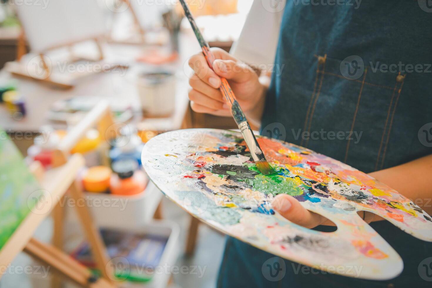 Close-up Art student's hand using a paintbrush to mix colors on a palette in hand to watercolor painting on canvas doing some art projects photo