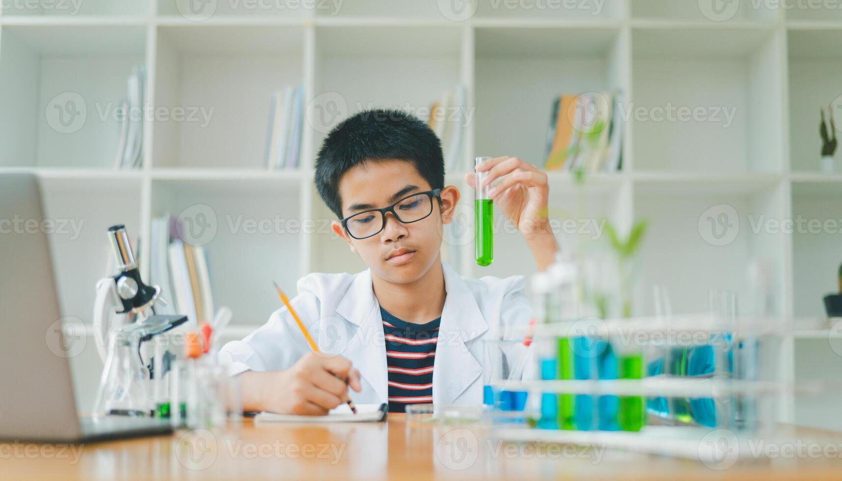 Asian male science students looking through a microscope and tests of plants in the classroom. Learning about scientific experiments on plant species. photo