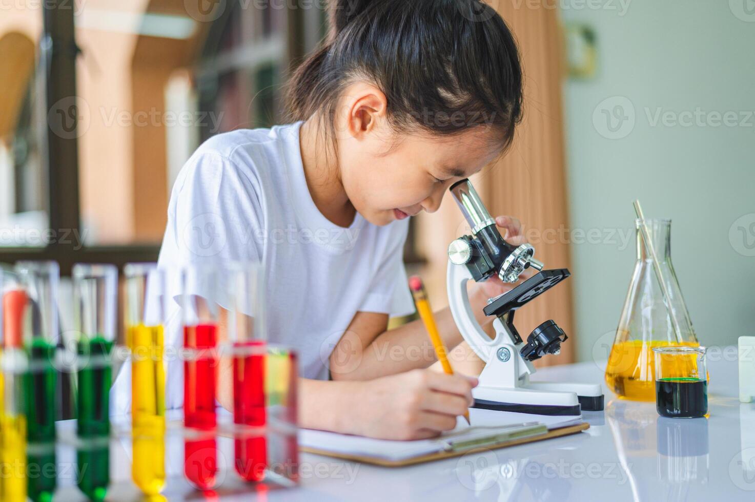 little scientist looking through a microscope and test tubes filled with chemicals for learning about science and experiments. photo