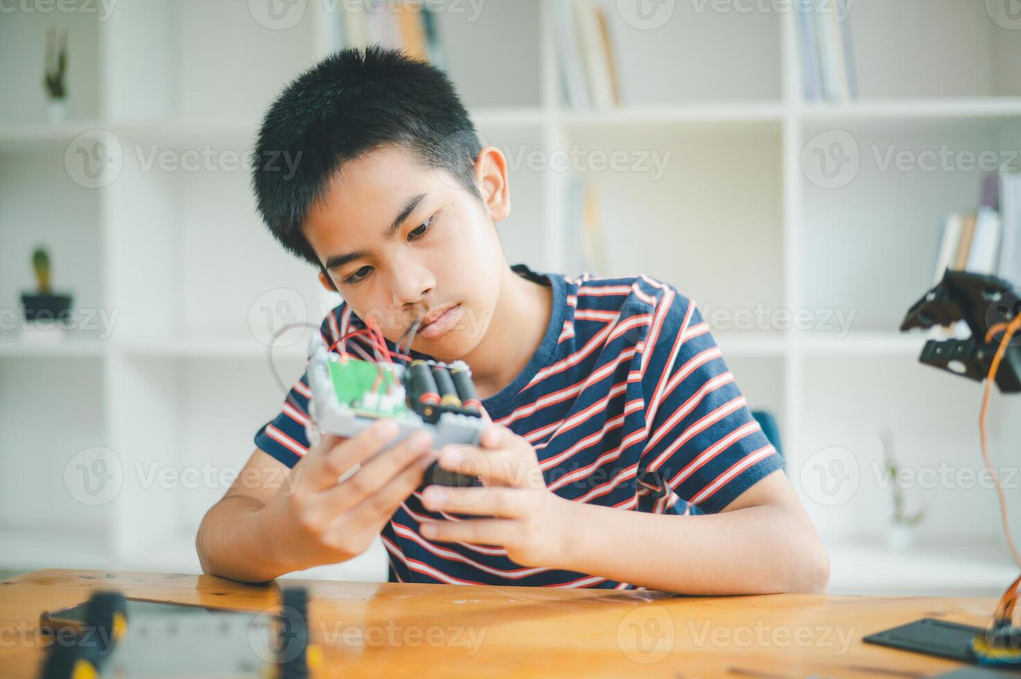 Asian boy learning and studying the work of technology robots.homeschool and science for tech project. playing childhood kids hobby leisure lifestyle people toys robotics technology. photo