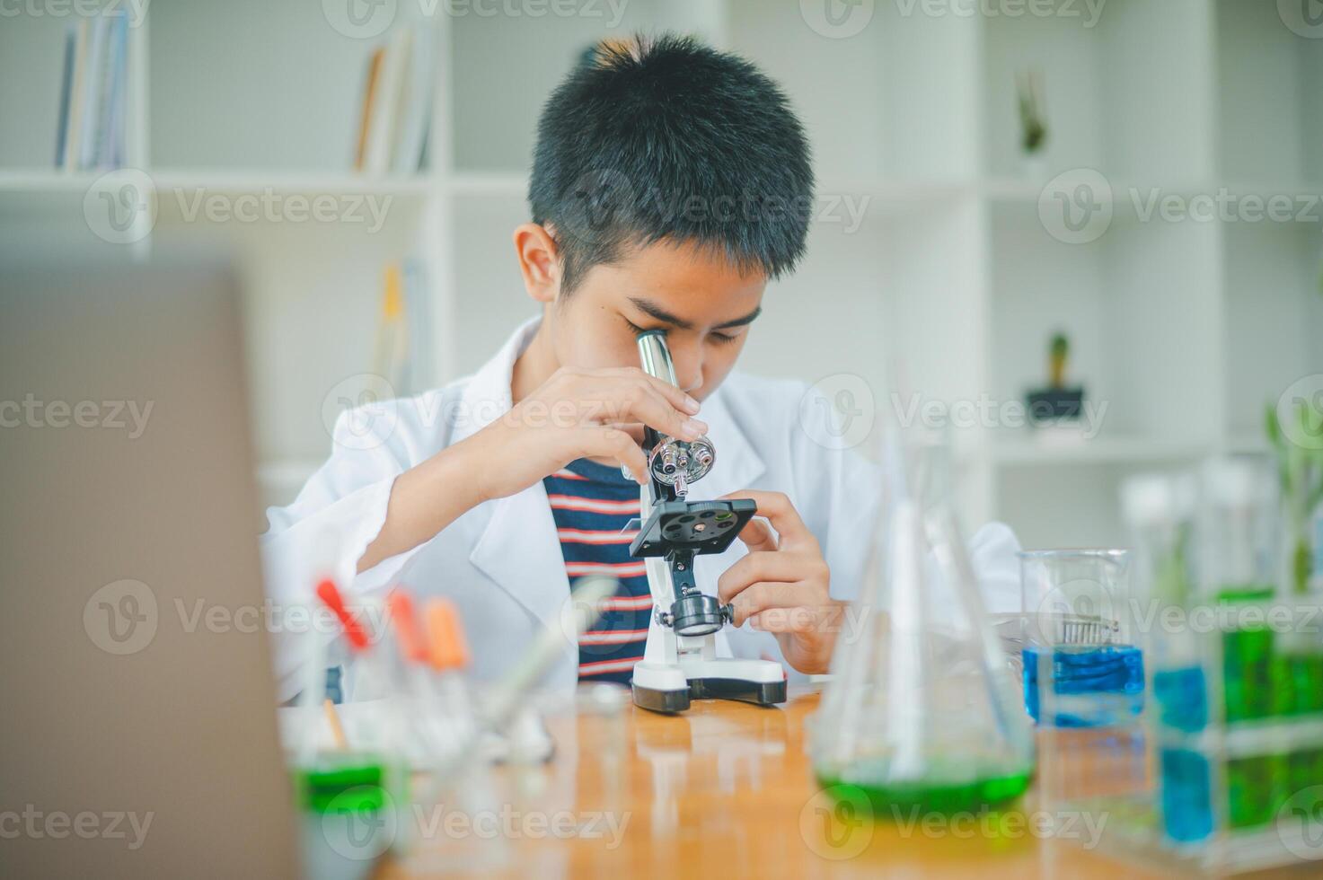 Asian male science students looking through a microscope and tests of plants in the classroom. Learning about scientific experiments on plant species. photo