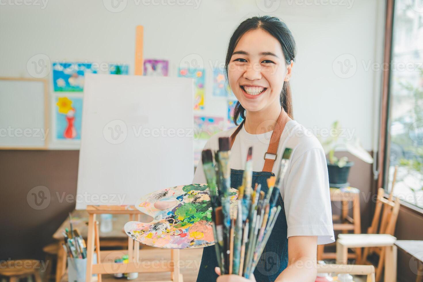 Portrait of Art student smiling happily while with watercolor painting on canvas doing some art projects on studio workshop photo