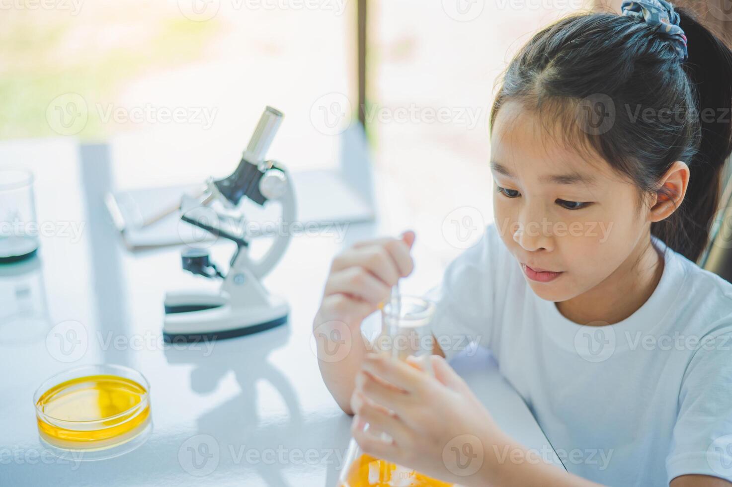 little scientist looking through a microscope and test tubes filled with chemicals for learning about science and experiments. photo