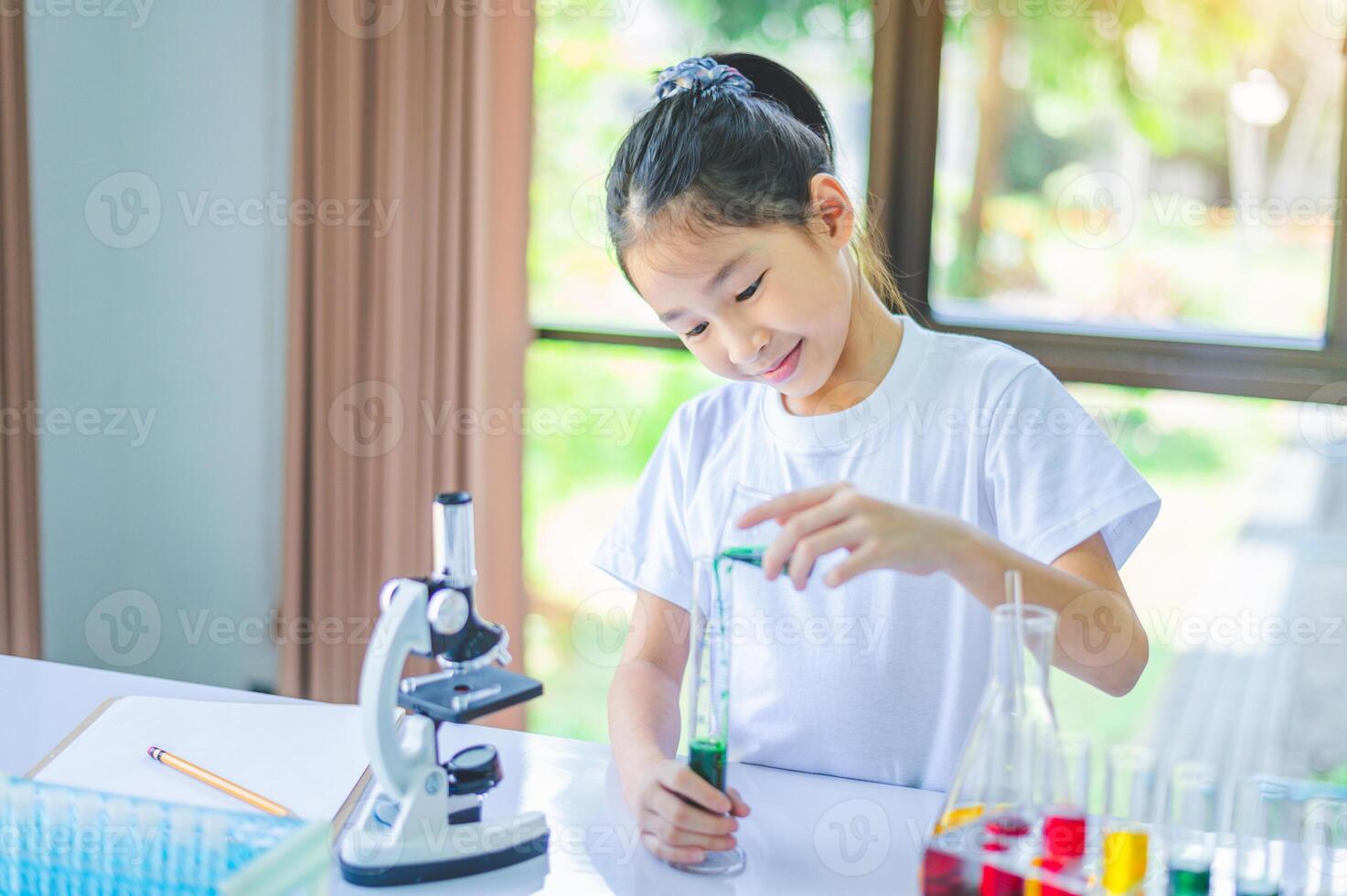 little scientist looking through a microscope and test tubes filled with chemicals for learning about science and experiments. photo