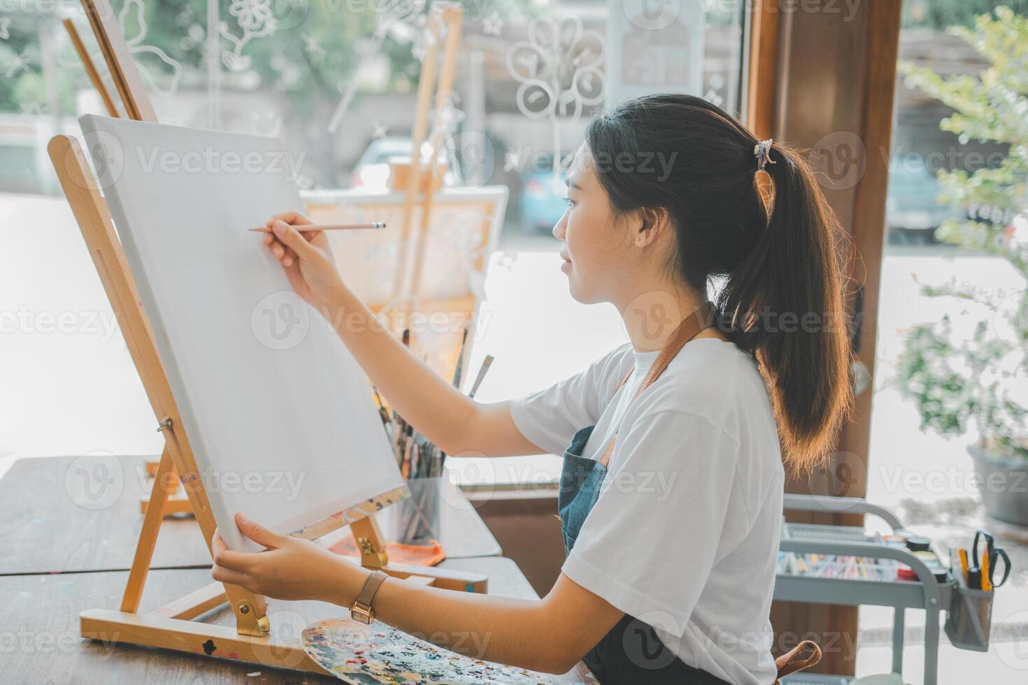 Art student drawing with watercolor painting on canvas doing some art projects on studio workshop photo