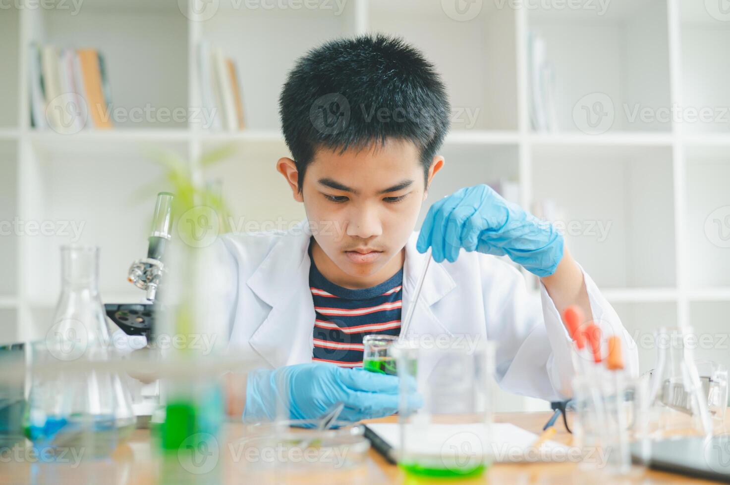 Asian male science students looking through a microscope and tests of plants in the classroom. Learning about scientific experiments on plant species. photo