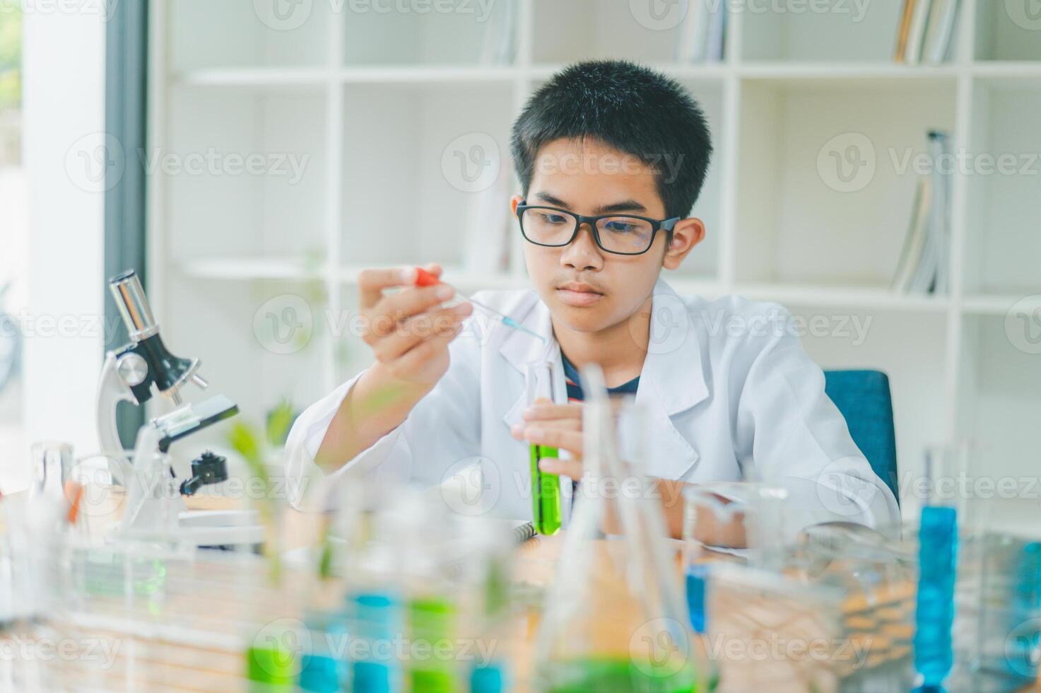 Asian male science students looking through a microscope and tests of plants in the classroom. Learning about scientific experiments on plant species. photo