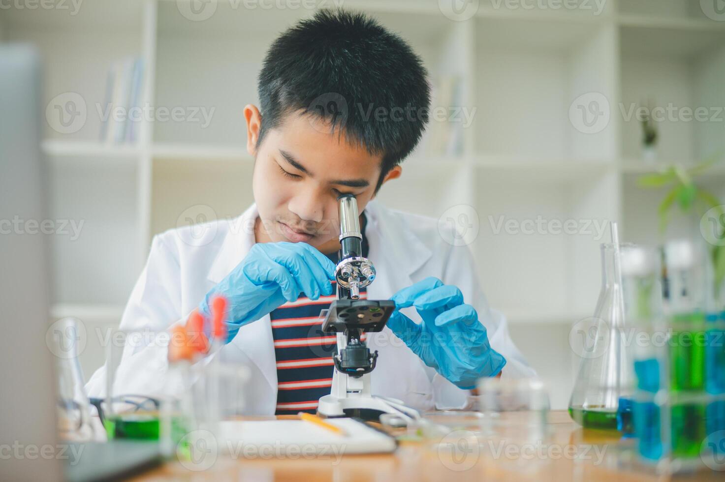 Asian male science students looking through a microscope and tests of plants in the classroom. Learning about scientific experiments on plant species. photo