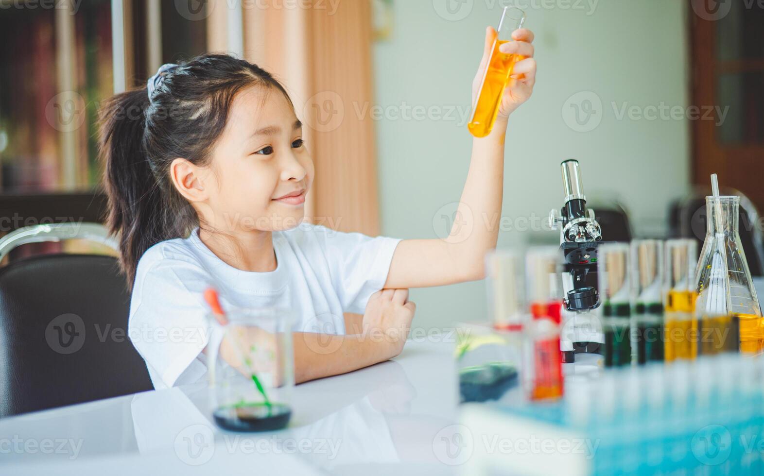 little scientist looking through a microscope and test tubes filled with chemicals for learning about science and experiments. photo