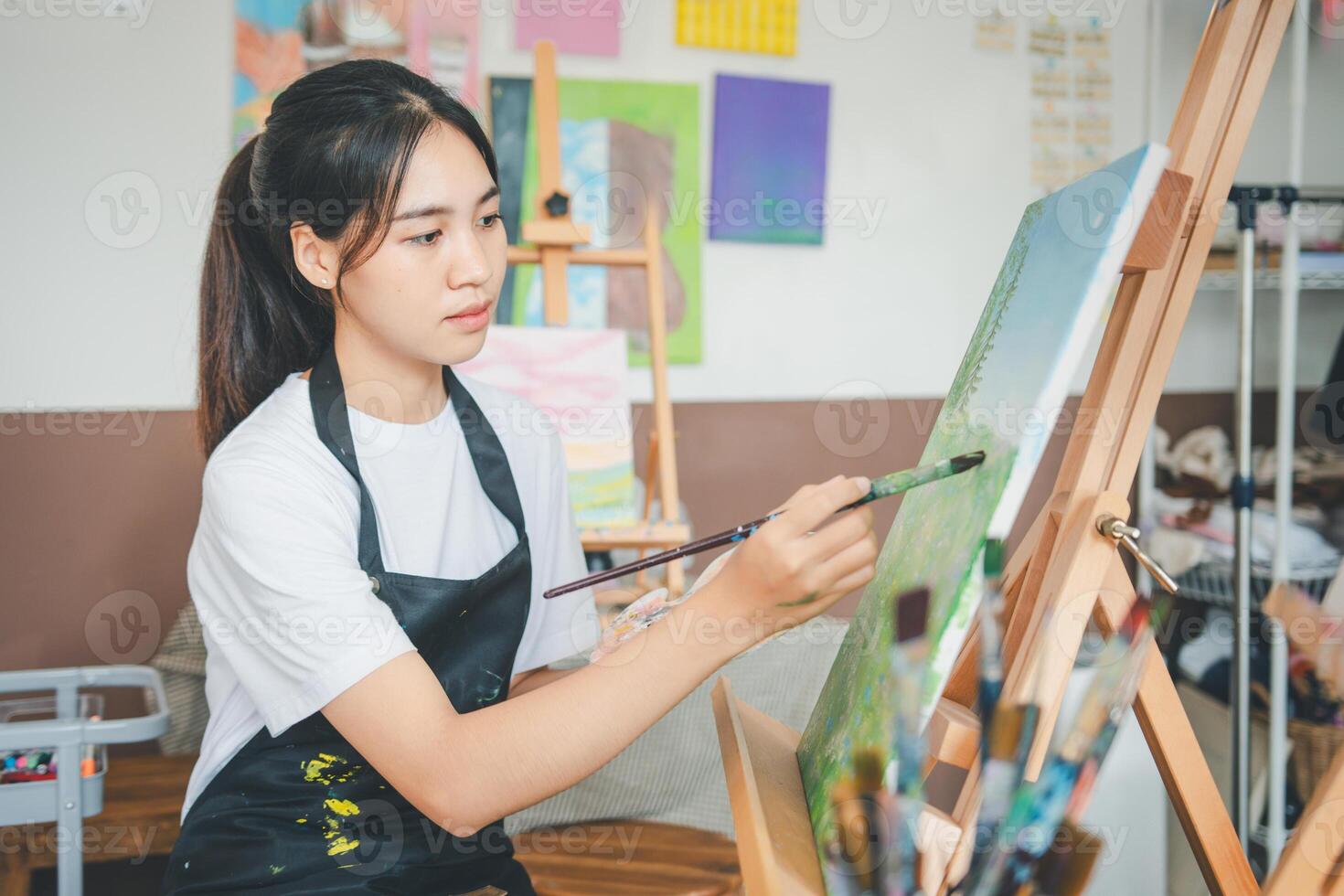 Art student drawing with watercolor painting on canvas doing some art projects on studio workshop photo