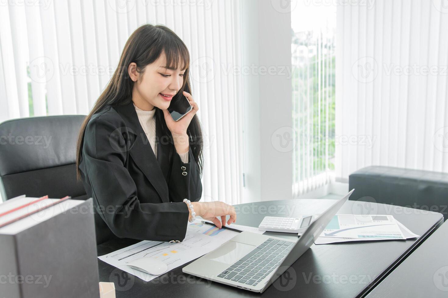 woman talking on the mobile phone and smiling while sitting at her working place in office. photo