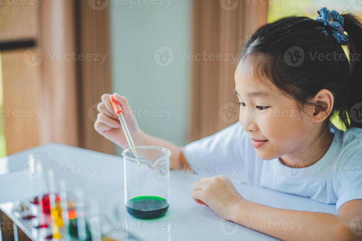 little scientist looking through a microscope and test tubes filled with chemicals for learning about science and experiments. photo