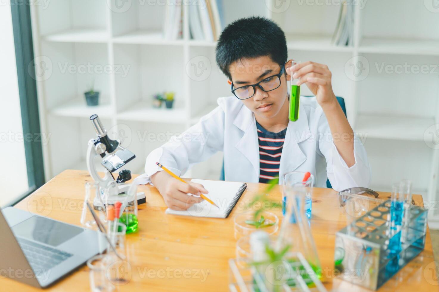 Asian male science students looking through a microscope and tests of plants in the classroom. Learning about scientific experiments on plant species. photo