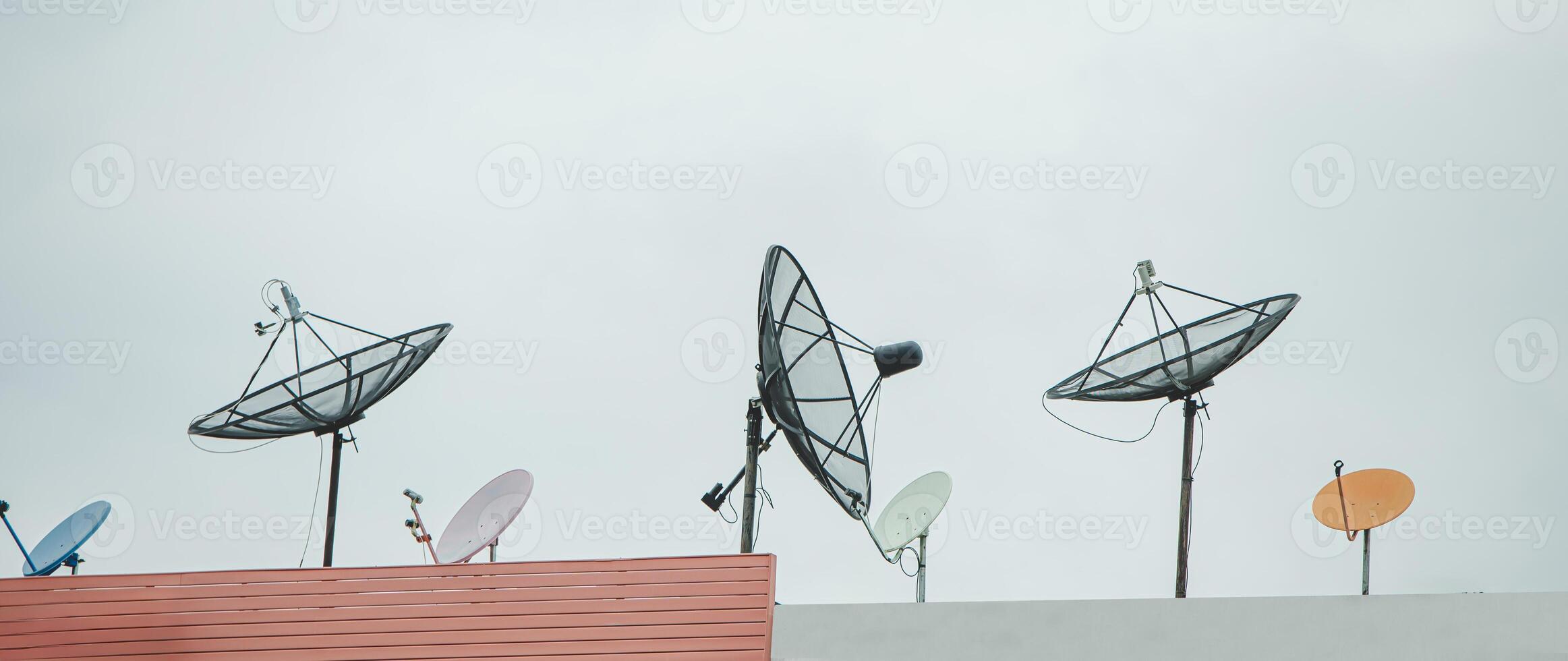 Many old communication satellite dishes expired and left on rooftops. photo