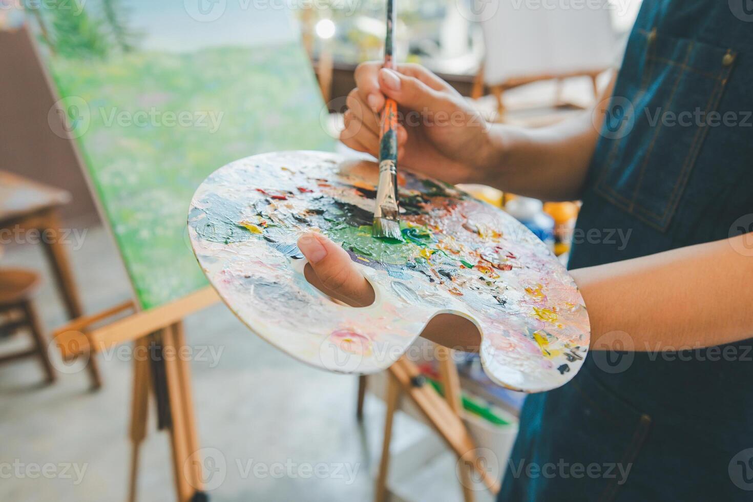 Close-up Art student's hand using a paintbrush to mix colors on a palette in hand to watercolor painting on canvas doing some art projects photo