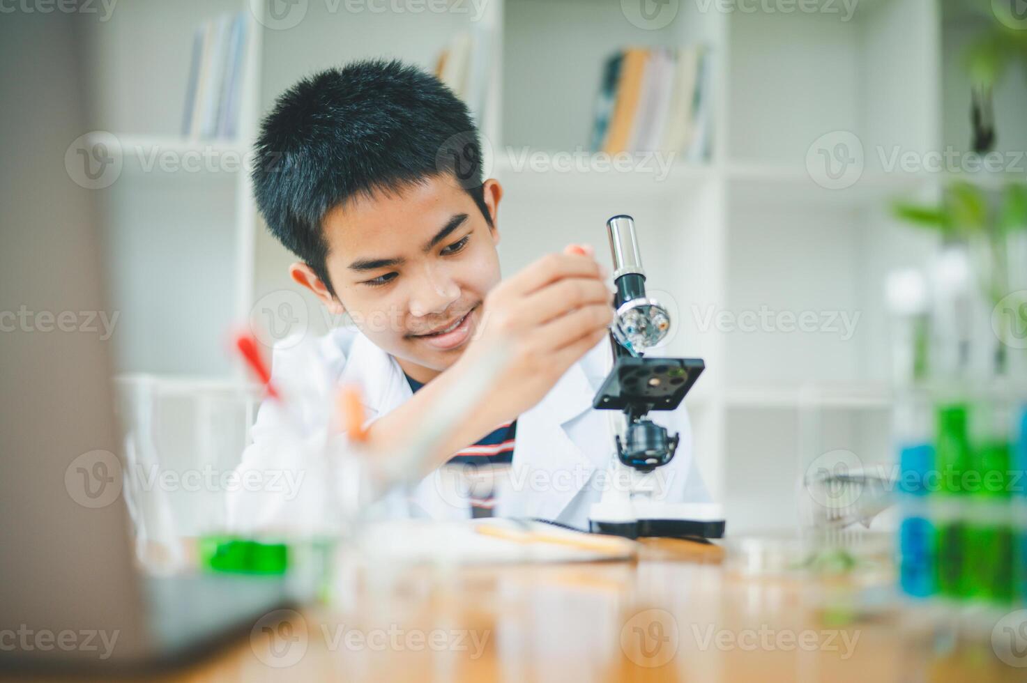 Asian male science students looking through a microscope and tests of plants in the classroom. Learning about scientific experiments on plant species. photo