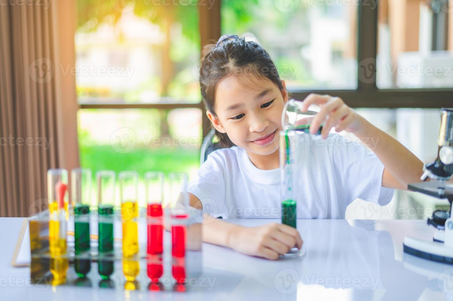 little scientist looking through a microscope and test tubes filled with chemicals for learning about science and experiments. photo