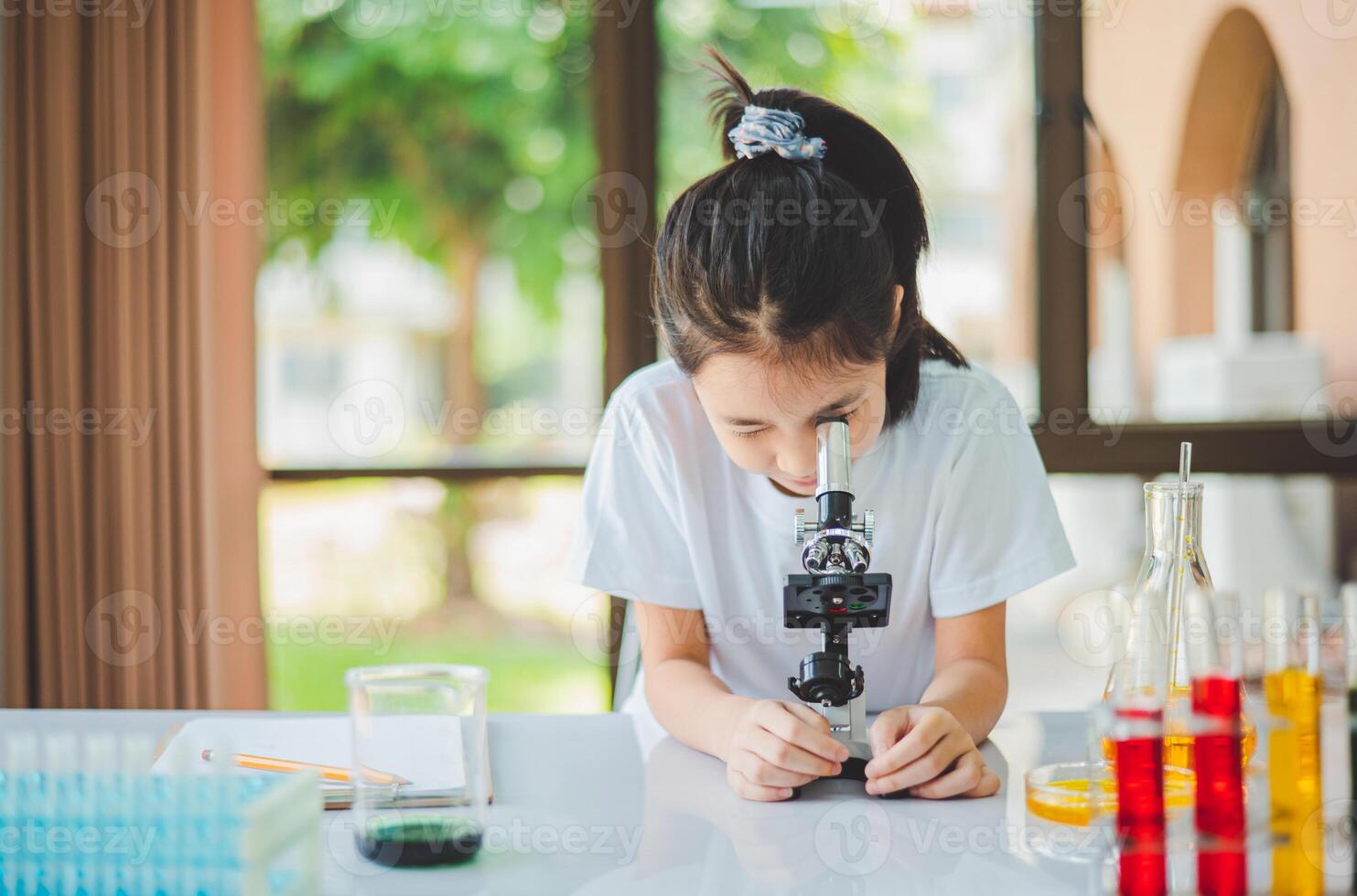 little scientist looking through a microscope and test tubes filled with chemicals for learning about science and experiments. photo