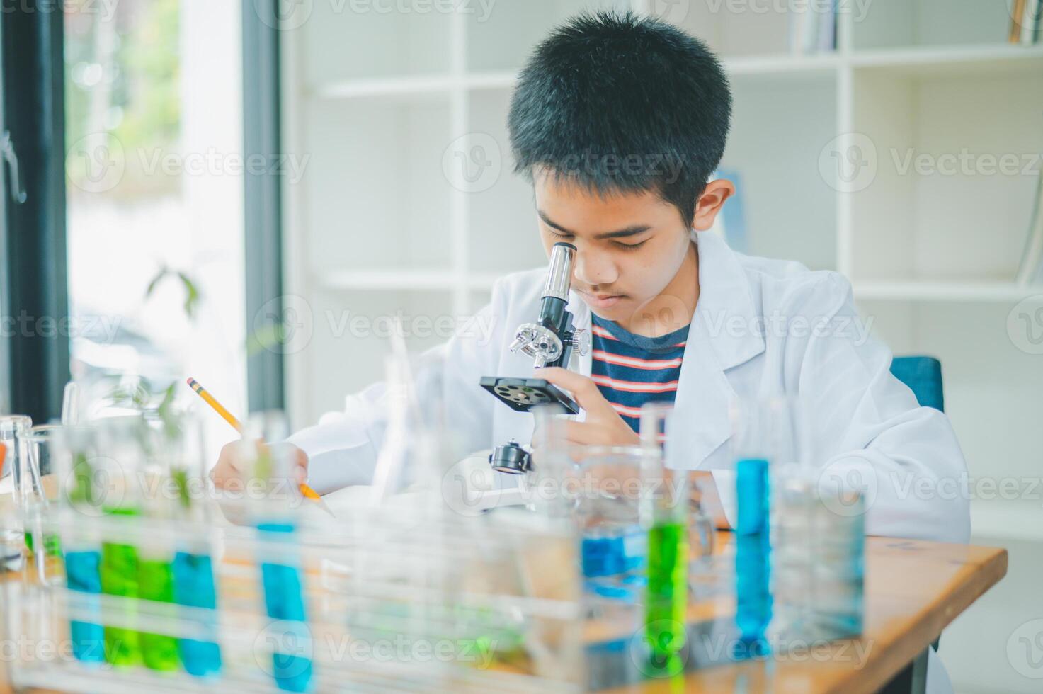 Asian male science students looking through a microscope and tests of plants in the classroom. Learning about scientific experiments on plant species. photo