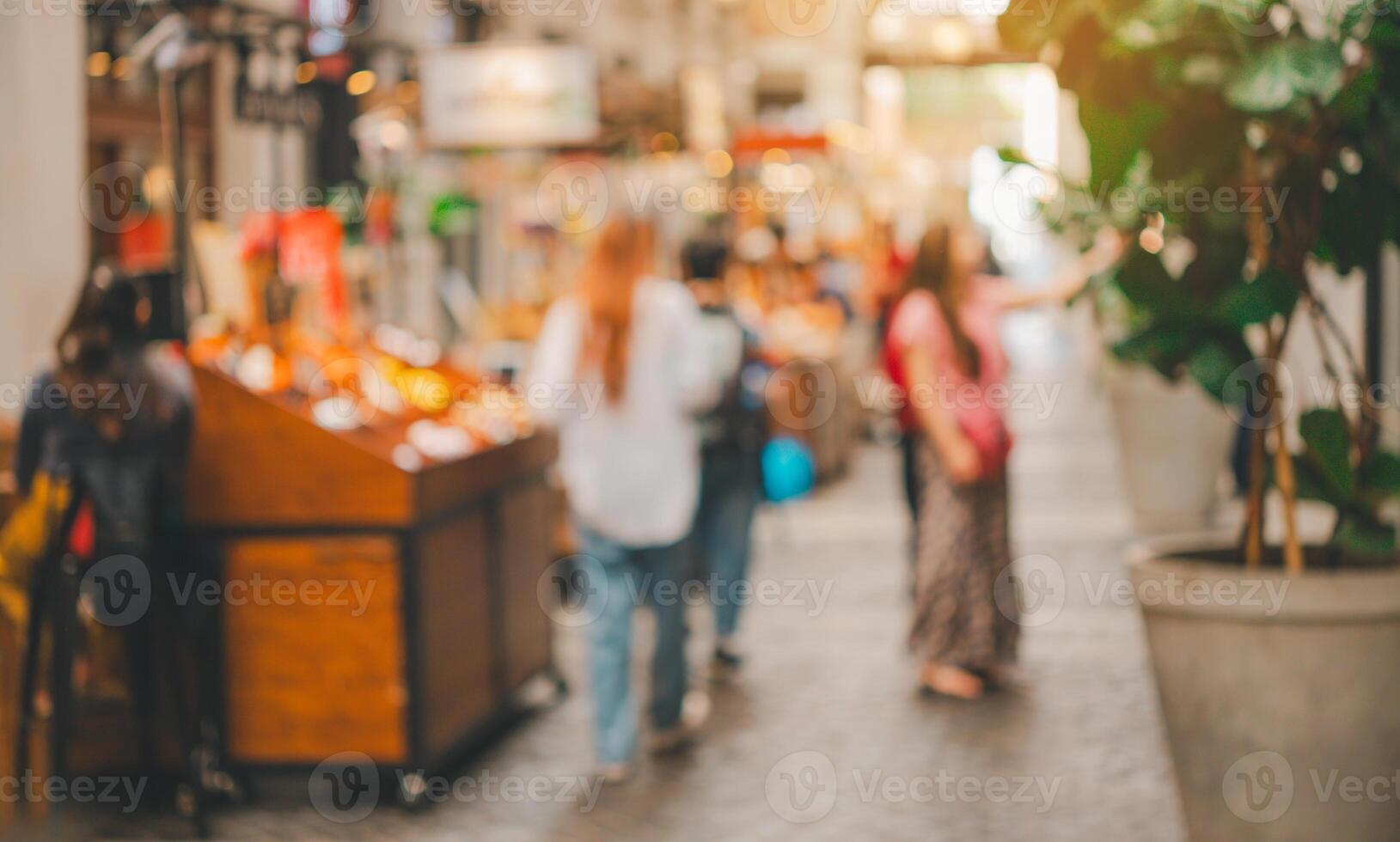 A blurry image of a busy street with people walking and shopping photo