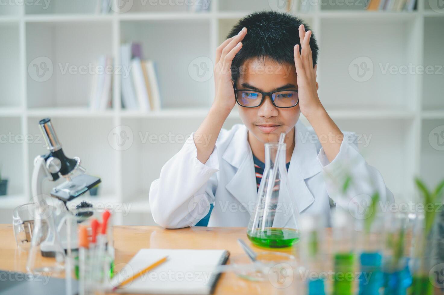 Asian male science students looking through a microscope and tests of plants in the classroom. Learning about scientific experiments on plant species. photo