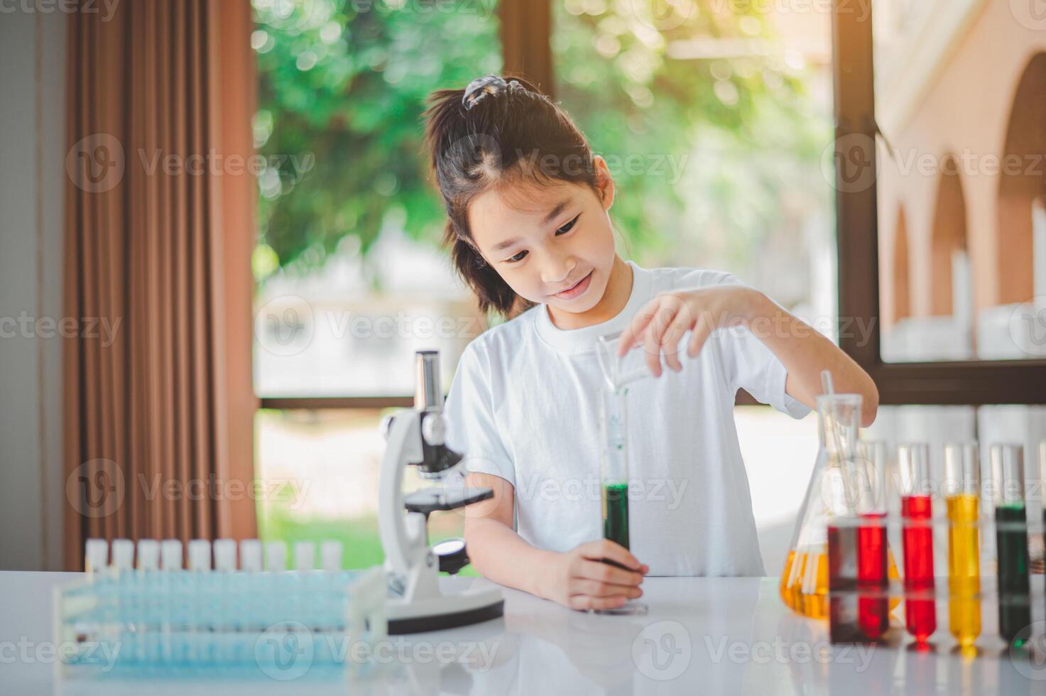 little scientist looking through a microscope and test tubes filled with chemicals for learning about science and experiments. photo