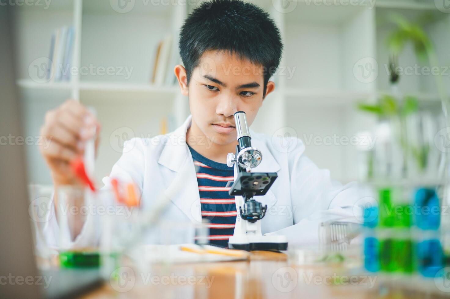 Asian male science students looking through a microscope and tests of plants in the classroom. Learning about scientific experiments on plant species. photo
