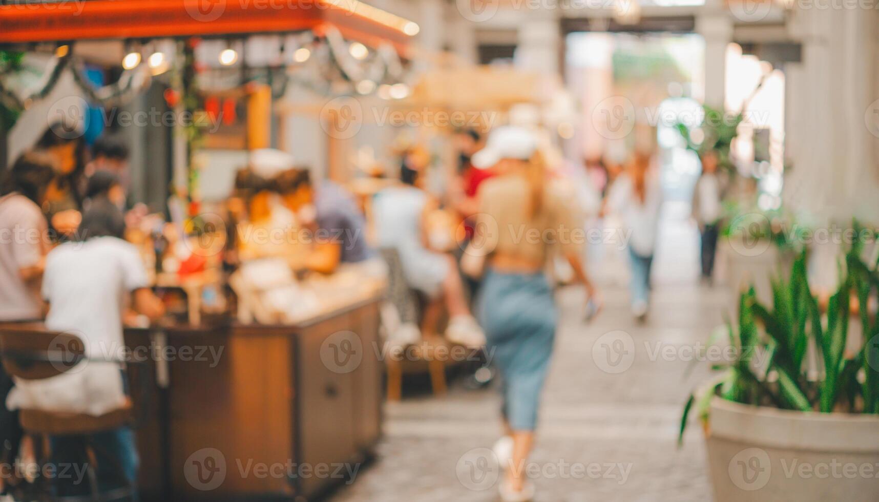 image blurry of the busy outdoor market with people walking around and sitting at tables photo