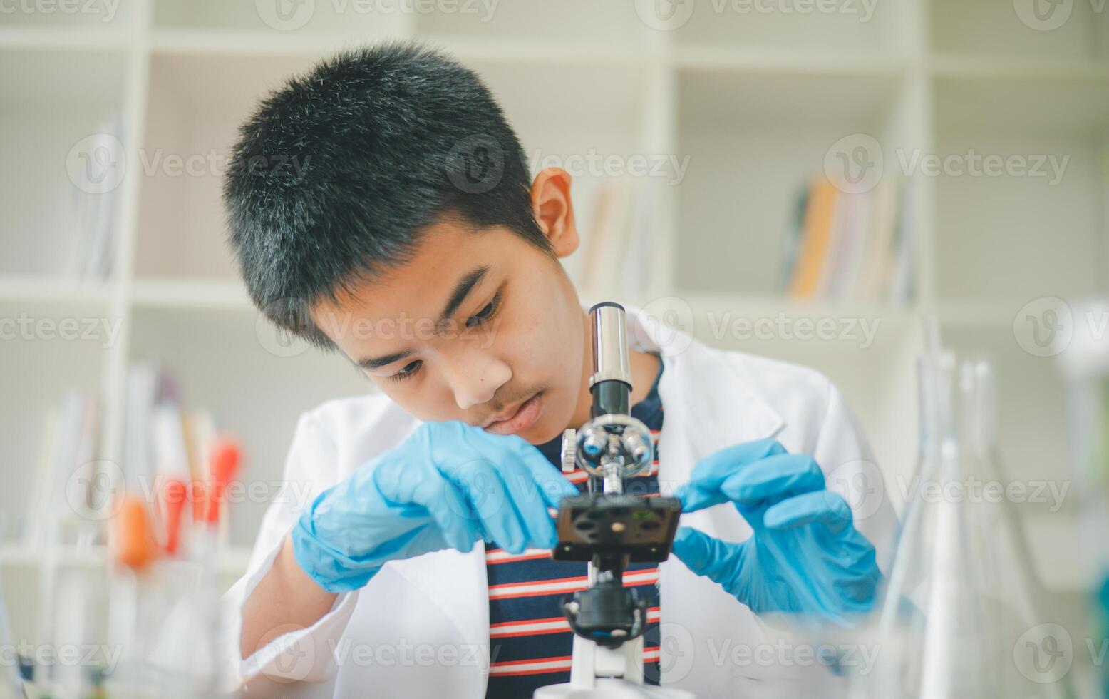 Asian male science students looking through a microscope and tests of plants in the classroom. Learning about scientific experiments on plant species. photo