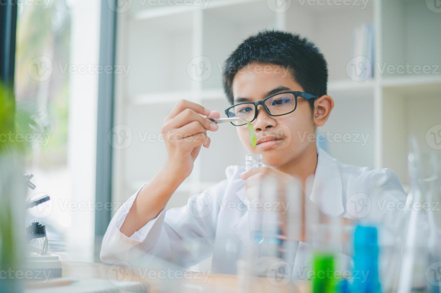 Asian male science students looking through a microscope and tests of plants in the classroom. Learning about scientific experiments on plant species. photo
