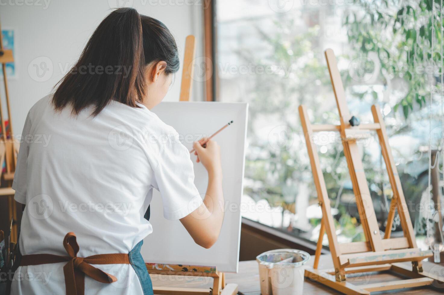 Art student drawing with watercolor painting on canvas doing some art projects on studio workshop photo