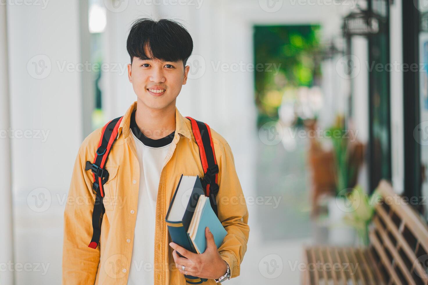 Happy smiling student with book in hand on campus while going to study for learning. photo