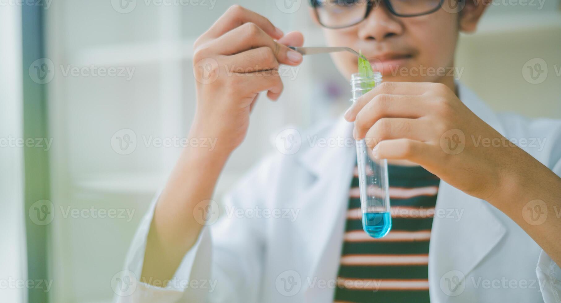 Asian male science students looking through a microscope and tests of plants in the classroom. Learning about scientific experiments on plant species. photo
