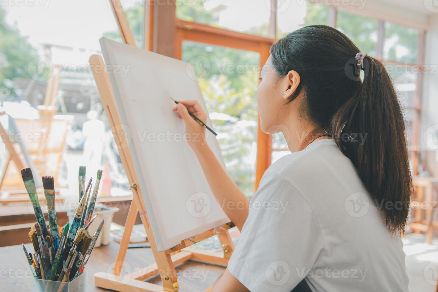 Art student drawing with watercolor painting on canvas doing some art projects on studio workshop photo