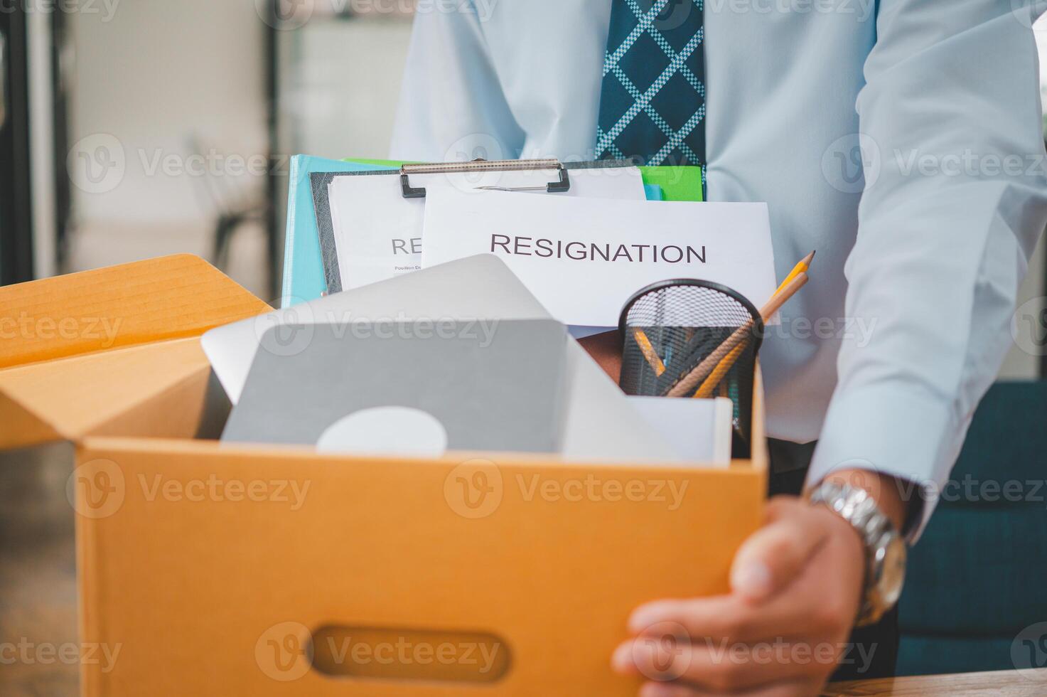 Young company employee packing office supplies and personal items in cardboard boxes before leaving the office to look for a new job, being fired, or being dismissed by the employer. photo