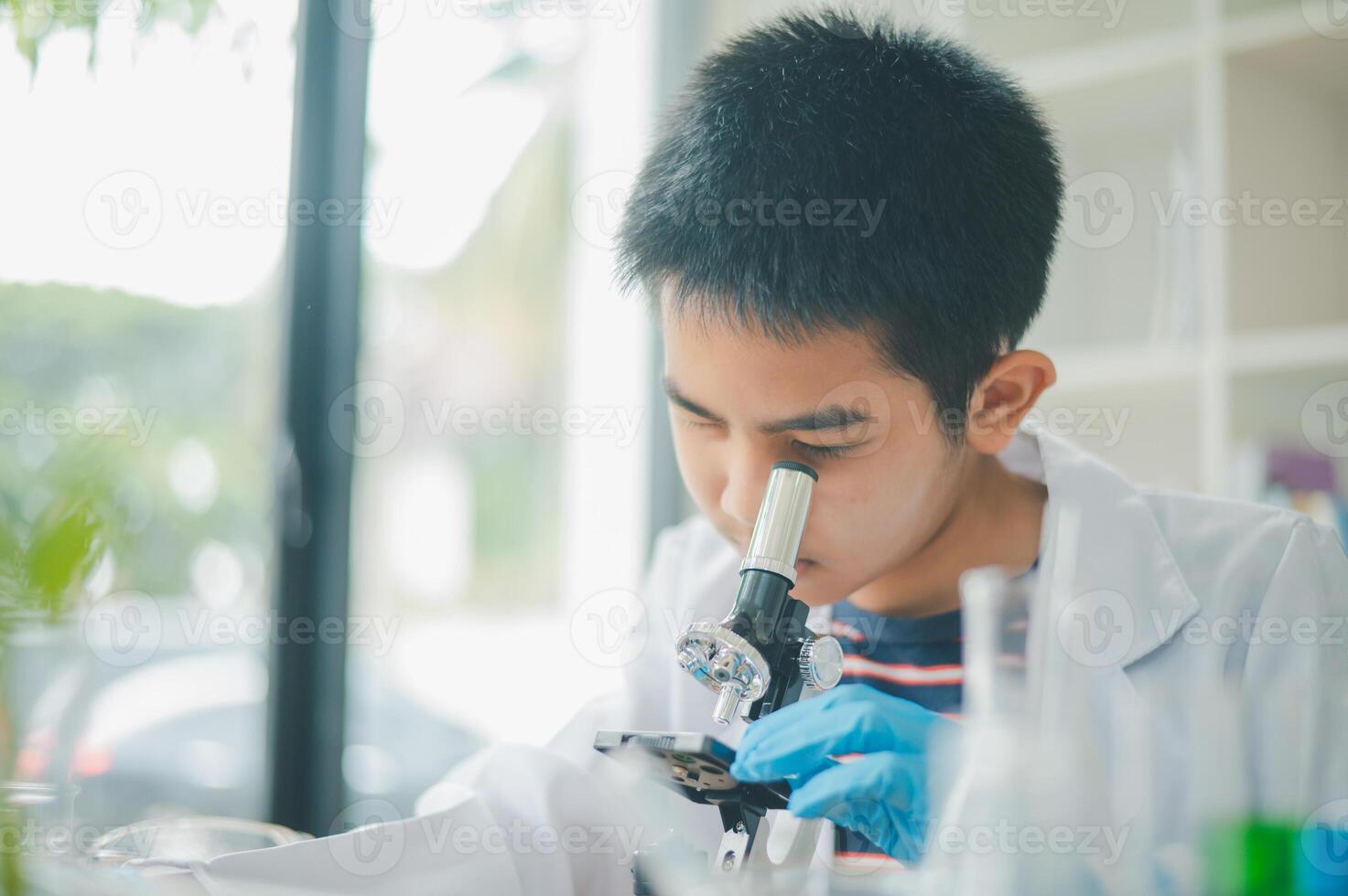 Asian male science students looking through a microscope and tests of plants in the classroom. Learning about scientific experiments on plant species. photo