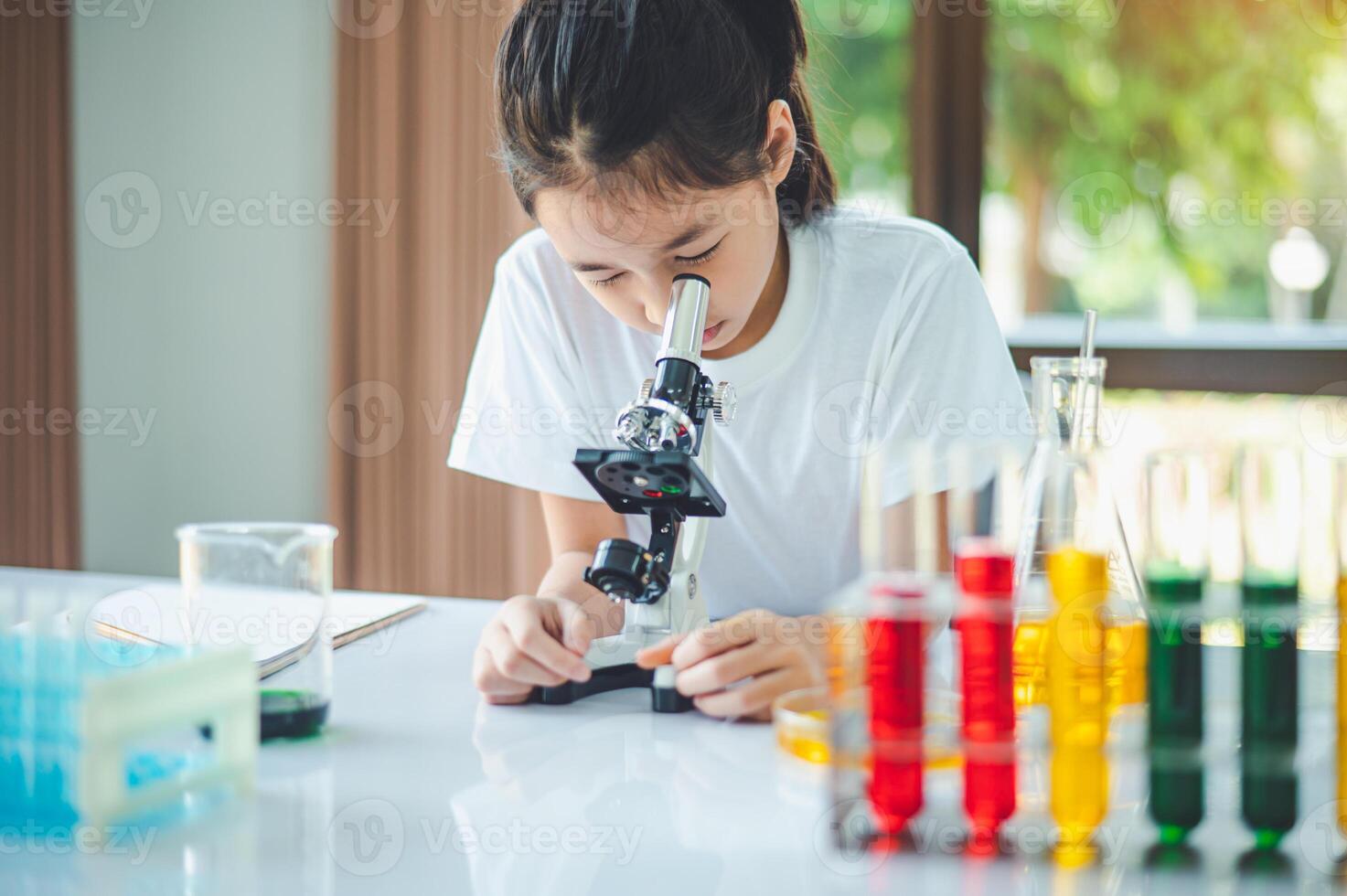 little scientist looking through a microscope and test tubes filled with chemicals for learning about science and experiments. photo