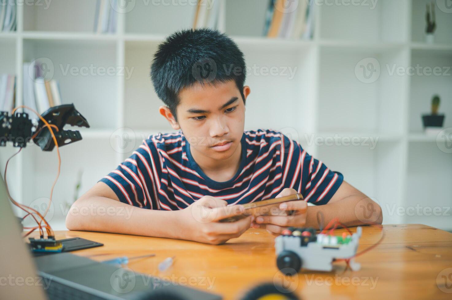 Asian boy learning and studying the work of technology robots.homeschool and science for tech project. playing childhood kids hobby leisure lifestyle people toys robotics technology. photo
