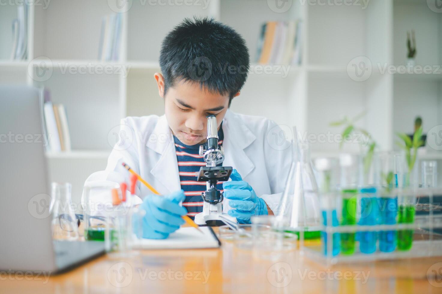 Asian male science students looking through a microscope and tests of plants in the classroom. Learning about scientific experiments on plant species. photo