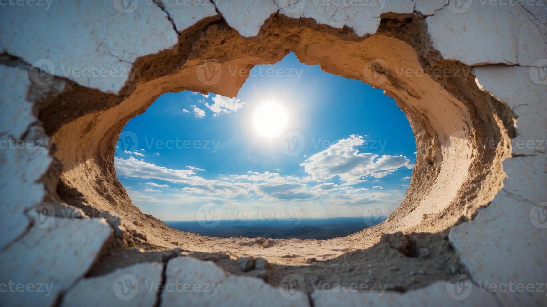 Blue sky and white clouds view through a hole in a cracked wall. photo