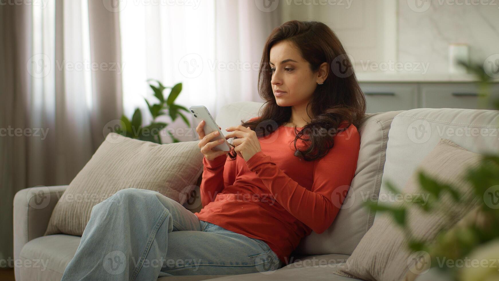 Shocked upset sad Caucasian troubled woman female girl client holding mobile phone cellphone reading bad news negative reaction no connection smartphone error failure losing online game at home couch photo